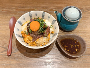 Delicious Gyudon with raw egg yolk and sliced beef on rice, served with sauce