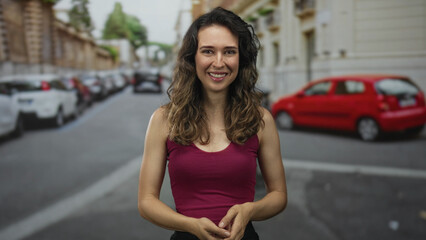 Smiling woman wearing red tank top clapping hands on city street; happiness celebration excitement joy.