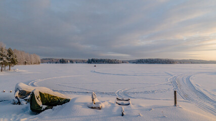 Aerial view of snow-covered expanses meeting the horizon under a soft sky, with subtle tracks etched into the pristine landscape, Joensuu, North Karelia, Finland.