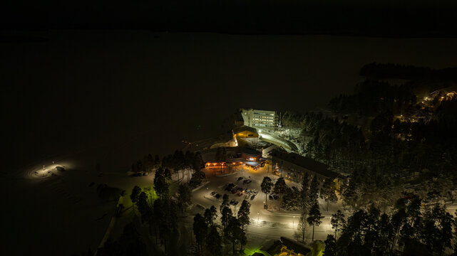 Aerial view of the illuminated Break Sokos Hotel Bomba nestled amidst the snow-covered landscape, Kontiolahti, North Karelia, Finland.