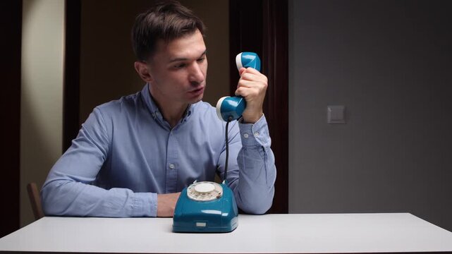 Man yells loudly on phone, Man exhibits intense anger while vocally arguing on vintage telephone, Furious individual passionately debates over phone showing clear signs of agitation and frustration