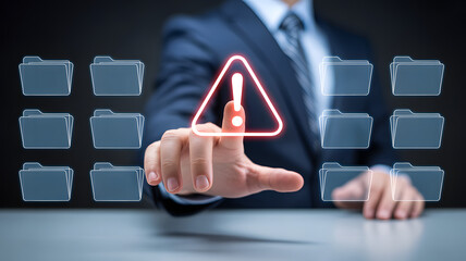 Businessperson pointing at digital warning icon with folder grid interface in cybersecurity concept