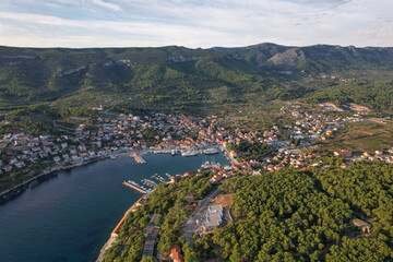 Aerial view of the harbor reflecting the sky, with charming buildings nestled between the sea and the verdant hills, Jelsa, Split-Dalmatia County, Croatia.