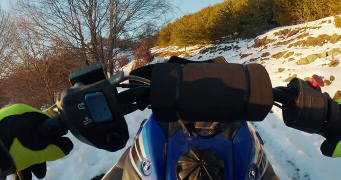 POV scene of rescuer man riding snowmobile on snowy mountain trail at sunset
