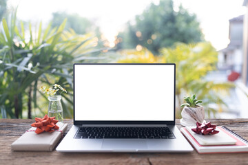Laptop and gift box arranged on wood desk, with balcony view