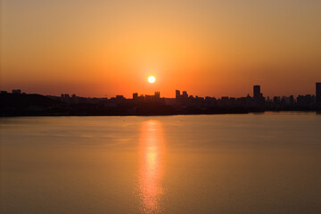 Sunset over lake with city buildings distant