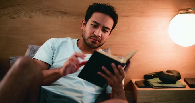 Reading, book and man on bed, relax and break with fiction novel, learning or knowledge in apartment. Calm, person and resting with literature in bedroom, hobby and comfortable with info in house