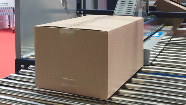 Ready-to-ship corrugated cardboard boxes on a blue conveyor belt at a distribution warehouse. Storage, logistics, delivery, warehouse concept background.