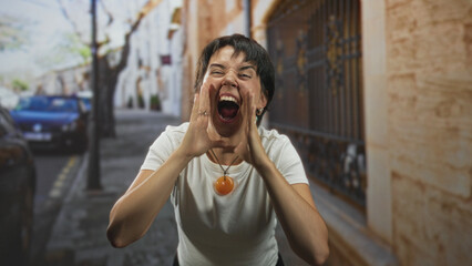 Woman shouting with hands cupped around mouth, short hair and orange pendant necklace on a street...