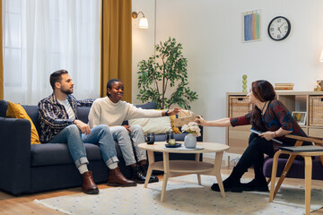 Diverse couple counseling with female therapist receiving document