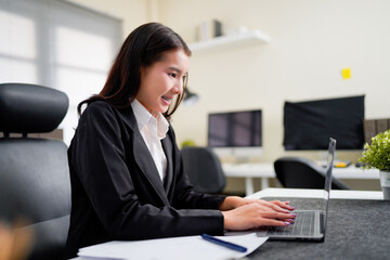 A businesswoman types on a laptop keyboard while a digital tablet with a reflection of her hand is on an office table, representing online work and remote employment.