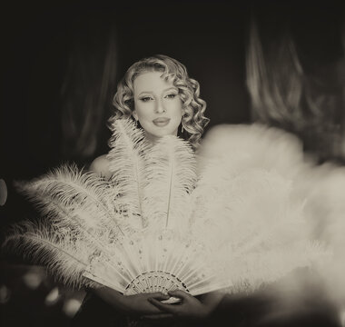 black and white color photo Beauty blonde hair retro lady looking into mirror hand holding fan natural ostrich feathers. sexy woman burlesque show actress. Flapper girl 20s roaring twenties old style