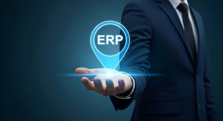 Businessman in dark suit presenting erp software on his hand with glowing blue interface on dark background