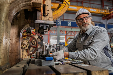 Industrial engineer inspecting heavy machinery during maintenance in a factory workshop. Focus on safety, precision, and mechanical engineering process for industrial equipment operation.