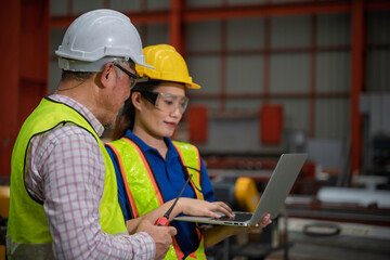 Engineer and technician inspecting materials on factory production line while discussing data on laptop. Great for industry, manufacturing, teamwork, and quality control concepts.