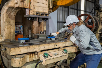 Industrial engineer inspecting heavy machinery during maintenance in a factory workshop. Focus on safety, precision, and mechanical engineering process for industrial equipment operation.