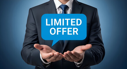 Businessman in suit holding limited offer speech bubble with hands outstretched towards the camera on blue background