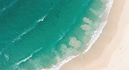 Aerial view of turquoise ocean waves gently lapping against a pristine sandy beach shore with white foam
