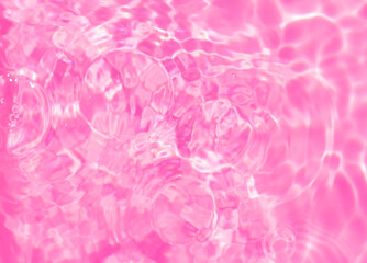 Fototapeta premium Close-up of calm pink clear water surface with water spray and bubbles. Trendy abstract summer nature background. Coral waves in sunlight