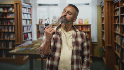 Man holding drill in library building, hand gripping tool and plaid shirt visible; confidence craft.
