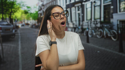 Woman adjusting glasses with hand on chin, arms crossed and wearing a white t shirt and watch on a...