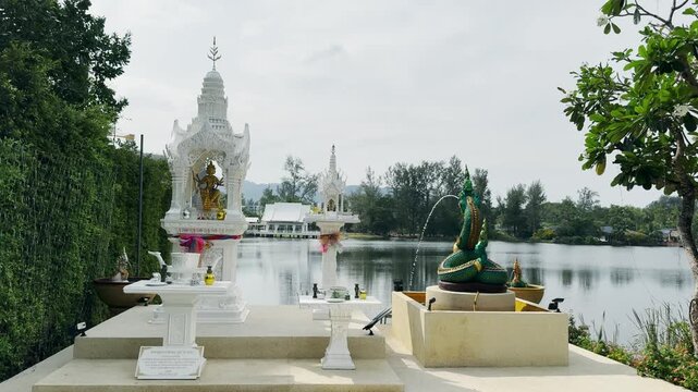 Elaborately designed Thai spirit houses near a calm riverside in Angsana in Puket, Thailand