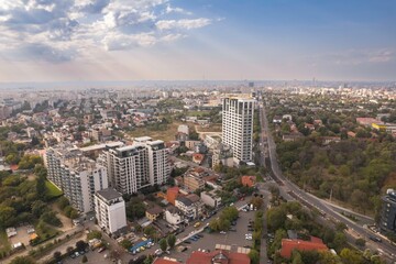 Fototapeta premium Buildings rise gracefully from the earth, showcasing modern architecture against a backdrop of a dramatic sky. Trees and parks add vibrant greenery to the urban landscape