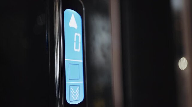 Businessman hand pressing elevator call button down on a touchscreen control interface in luxury modern loby