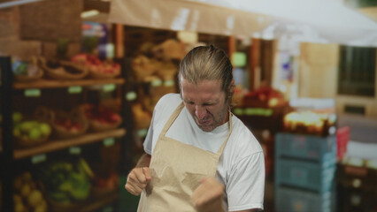 Blond man with long hair clenches fists beside fruit display in bustling grocery store aisle;...