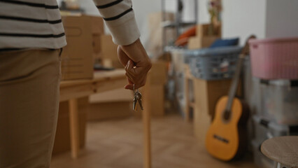 Man holding keys in a new home living room with packing boxes in the background symbolizing moving and relocation concepts in a cozy apartment.