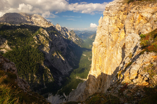 Aerial view of golden sunlight illuminating the cliff face as it peers over the lush green valley in the Julian Alps, Srenjska Krma, Radovljica, Slovenia.