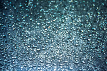 Close-up of water droplets reflecting sunlight on a surface, creating a beautiful bokeh effect