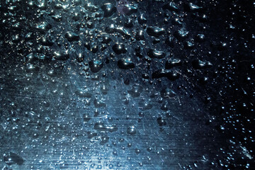 Close-up of water droplets reflecting sunlight on a surface, creating a beautiful bokeh effect