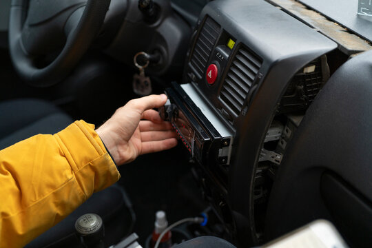 Person is working on installing a car radio in a vehicle's dashboard in a garage setting
