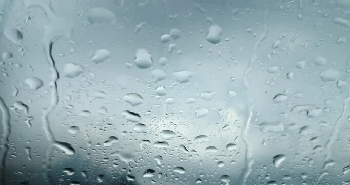 Raindrops on a glass window with a stormy sky background
