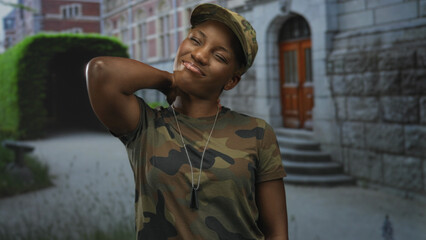 Young african american woman soldier in camouflage uniform with dogtag chain holds neck with hand...
