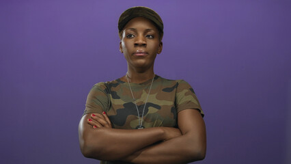 Obraz premium Woman in camouflage uniform crosses arms showing military dog tags in studio and gazes ahead with a stoic expression; pride.