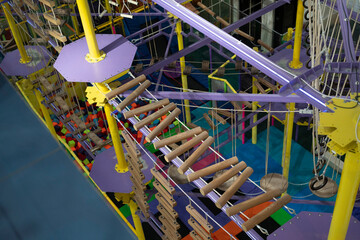 Visitors navigate a climbing area with beams, ropes, and various colorful obstacles for play