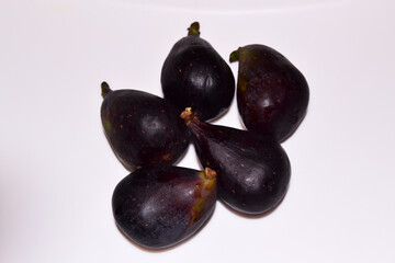 Five fresh whole black blue figs on wite background