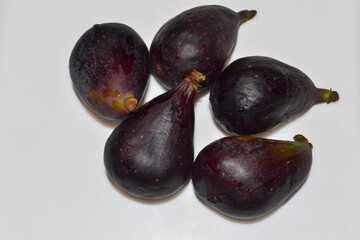 Five fresh whole black blue figs on wite background