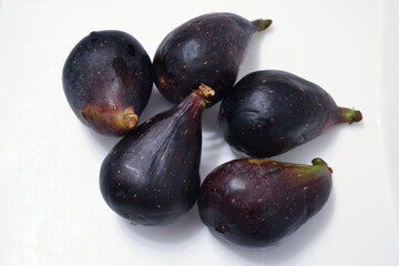 Five fresh whole black blue figs on wite background