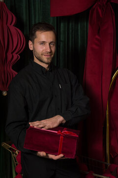 A young handsome man in a black shirt holds a gift in his hands
