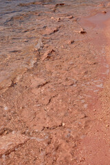 Tranquil shoreline with gentle waves lapping against pink sand beach