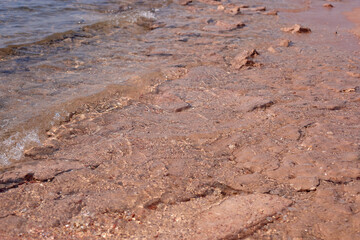 Textured shoreline with gentle waves lapping against rocky surface