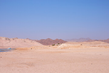 Expansive desert landscape with distant mountains under clear blue sky