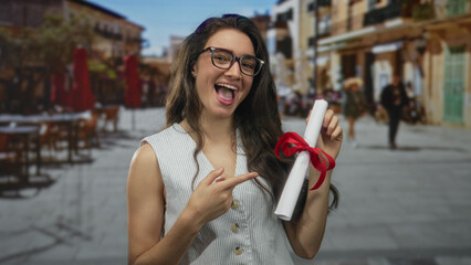 Woman holding rolled diploma tied with red ribbon pointing finger to document on busy city street;...