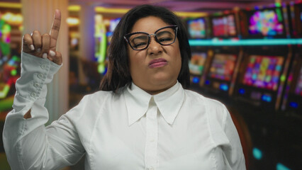 Fototapeta premium Woman pointing wearing glasses in a casino surrounded by slot machines captures a curious moment of decision and introspection.
