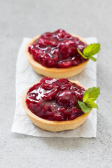 Two Vegan Cherry Round tartlets. With cream and mint. Light gray background