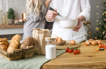 Man and woman preparing food in kitchen for Christmas holiday. Couple baking festive meal for dinner. Christmas recipe for family gathering.