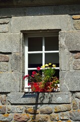 Ventana adornada con flores en Locronan, Bretaña, Francia
